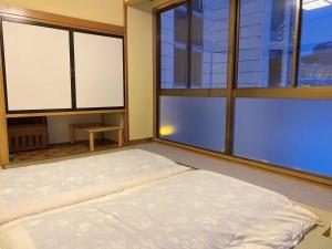 Bett in einem Zimmer mit zwei großen Fenstern in der Unterkunft Minamiuonuma - Hotel - Vacation STAY 36571v in Seki