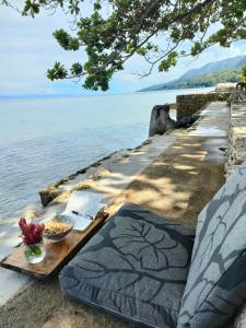een tafel met een laptop en een kom eten naast het water bij Sea Me in Kansaloay