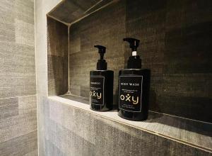 twee zwarte shampoo flessen op een plank in een badkamer bij oxy suites G-03 at Shop House Meisterstadt Pollux Habibie in Batam Center