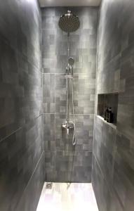 a bathroom with a shower with gray tiles at oxy suites G-03 at Shop House Meisterstadt Pollux Habibie in Batam Center