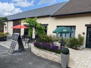 a restaurant with tables and chairs and an umbrella and flowers at Domaine Pierre Monnaie in Verzy