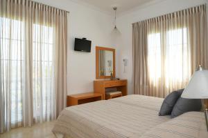a bedroom with a bed and a mirror and windows at Skalidis Apartments in Tolo