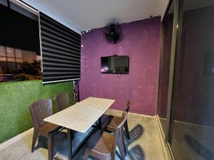 una mesa y sillas en una habitación con una pared púrpura en Ayden Hostel Airport Transit - KLIA, en Sepang