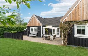 un patio trasero con una casa y una mesa con sombrilla en Tisvildelund, en Vejby