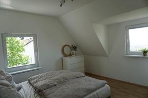 um quarto branco com uma cama e 2 janelas em Ferienhaus mit schöner Aussicht em Weitersburg