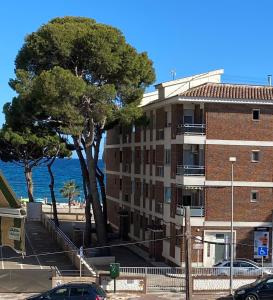 a building next to the ocean with a tree at Tranquilidad y confort, Apartamento reformado en Cambrils in Cambrils