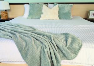 a bed with a green and white blanket on it at Апартамент FLAME in Sunny Beach