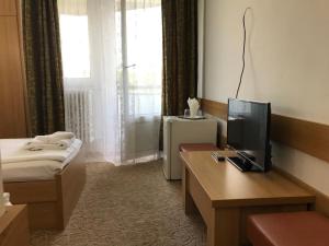 a hotel room with a bed and a television on a desk at Hotel Hefaistos - Sovata in Sovata