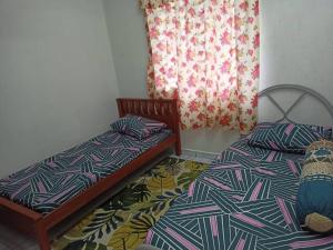 Duas camas sentadas uma ao lado da outra num quarto em Homestay Tokwan Besar & Selesa! em Batu Kikir