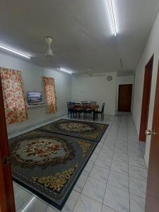 uma sala de estar com dois tapetes e uma mesa e cadeiras em Homestay Tokwan Besar & Selesa! em Batu Kikir