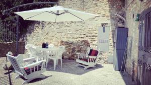 einen weißen Tisch und Stühle sowie einen Regenschirm auf einer Terrasse in der Unterkunft Casa di Duccio in Montone