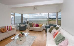 una sala de estar con sofás y sillas y una gran ventana en Clonea Beach Houses en Dungarvan