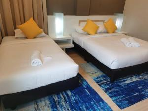 two beds in a room with yellow and white pillows at Lovita Hotel Kuantan in Kuantan