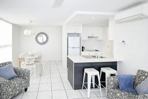 a kitchen and living room with a counter and chairs at Beachfront Choices Choices Choices in Alexandra Headland