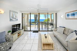 a living room with a couch and a tv and a table at Beachfront Choices Choices Choices in Alexandra Headland