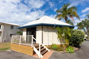 a small white house with a porch and a palm tree at NRMA Forster Tuncurry in Tuncurry