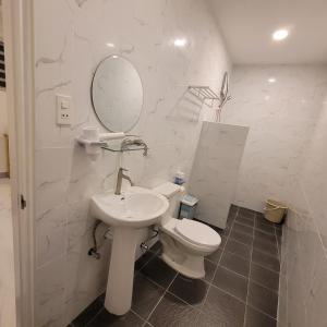 een badkamer met een toilet, een wastafel en een spiegel bij TuloMir #A 뚤로미르 행복한 4인실 in Moalboal