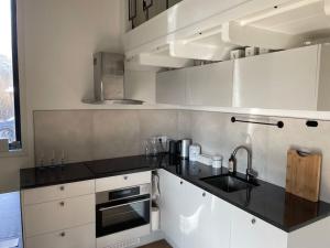 a kitchen with white cabinets and a black counter top at Nyrenoverat strandnära med fantastisk utsikt in Rimbo
