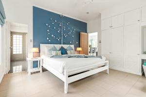 a bedroom with a white bed with a blue wall at 2BR Villa Baan Orchid, seconds to beach in Lamai
