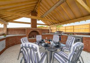 a patio with a table and chairs and a fireplace at Bowjy in Menheniot