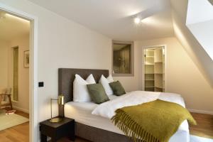 Schlafzimmer mit einem Bett mit weißer Bettwäsche und grünen Kissen in der Unterkunft SAXX Apartments Leipzig in Leipzig