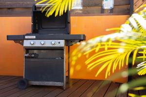 an outdoor grill with a stove with an orange wall at Magnifique villa 8 personnes avec piscine au sel in Saint-Pierre