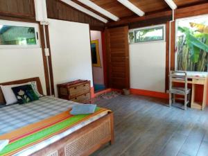 a bedroom with a bed and a desk and two windows at Kokrobite Gardens Restaurant and Guest House in Kokrobite
