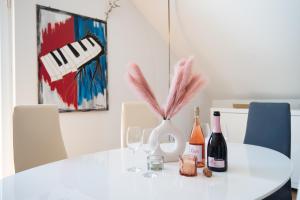 a white table with wine glasses and a vase with pink feathers at Milic Apartments - by the sea in Sutivan