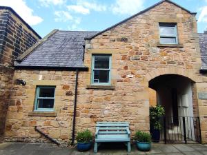 un edificio in pietra con una panchina di fronte di Dodds Nook ad Alnwick