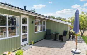 una casa verde con patio e ombrellone di 2 Bedroom Amazing Home In Sby a Sæby