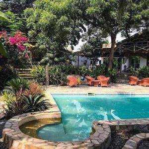 una piscina en un patio con mesas y sillas en Kokrobite Gardens Restaurant and Guest House, en Kokrobite