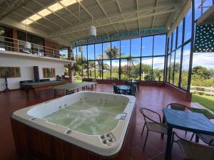 Una gran bañera en una habitación con mesas y sillas. en Finca Hotel 12 Palmas- Aeropuerto JMC, en Rionegro