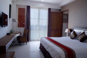 a hotel room with a large bed and a desk at Hotel on The Rock in Kupang