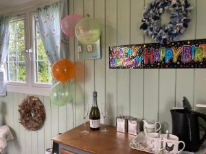 a table with two glasses of wine and balloons at Bells Meadow Shepherds Hut in King's Lynn