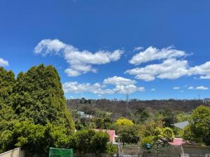 un cielo azul con nubes sobre los árboles en Heart of Katoomba Semi 1 bedroom home, en Katoomba