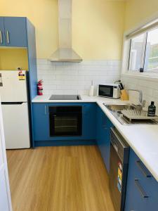 Una cocina con gabinetes azules y un refrigerador blanco. en Heart of Katoomba Semi 1 bedroom home, en Katoomba