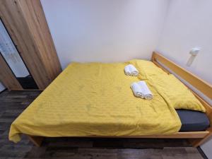 Un dormitorio con una cama amarilla con toallas. en T&A, en Paraćin