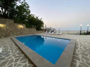 una grande piscina con muro in pietra e acqua blu di Tyupebi a Sighnaghi