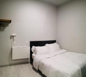 1 dormitorio con cama blanca y cabecero negro en LILO Staycation JQ, en Kota Kinabalu