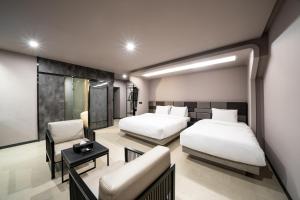 全州市Jeonju Jazz Around Hotel的有两张床和一张沙发的酒店房间