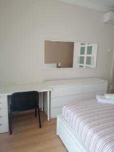 a white bedroom with a desk and a bed at Casa do Zé in Setúbal