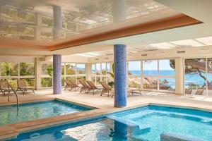 a swimming pool in a house with a view of the ocean at Universal Hotel Lido Park & Spa in Paguera