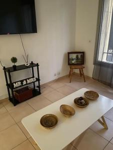 a living room with a white table with four bowls on it at Charmant logement proche de la mer in Florensac