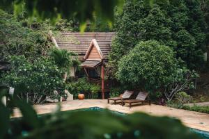 ein Pool mit zwei Stühlen und ein Haus in den Bäumen in der Unterkunft Kooncharaburi Resort - Koh Chang in Ko Chang