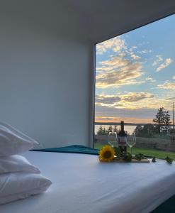 a bedroom with a window with wine glasses and a flower on the bed at Domek nad jeziorem in Kruklanki