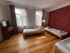 a room with two beds and a tv and two windows at Dzintari in Ventspils