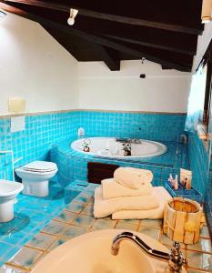 a blue tiled bathroom with a tub and a sink at Villa sarda in Assemini