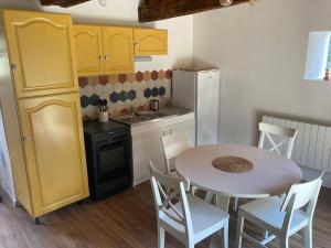 eine Küche mit einem weißen Tisch und Stühlen sowie eine Küche mit gelben Schränken in der Unterkunft Maison, Le Champ du Rossignol in Beuvron-en-Auge