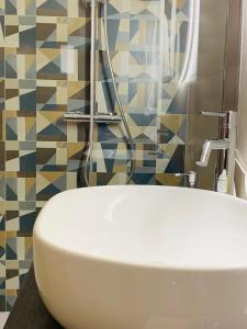 un bagno con lavandino bianco e parete a mosaico di Il Pilone a Barletta