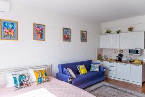 uma sala de estar com um sofá azul e uma cozinha em Студия в центре города, в «Золотом квадрате» em Almaty